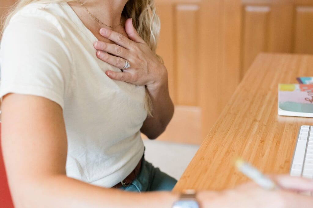 Parent resting a hand on her chest, pausing to check in with her own nervous system before responding.